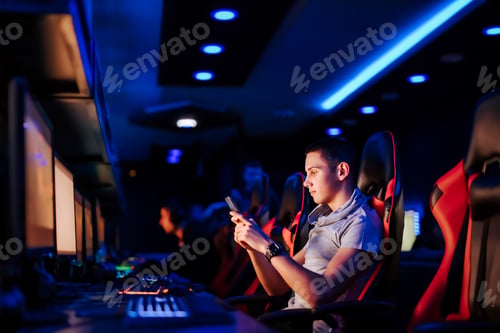 Preview: Cute teenager using smart phone at cybercafe, side view, portrait.