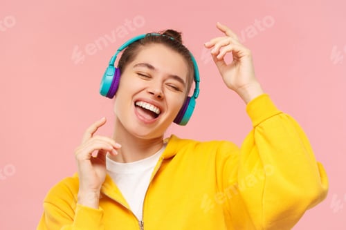 Preview: Portrait of young woman dancing to favorite music she is listening in wireless headphones