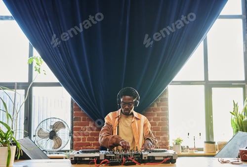 Preview: Young man in headphones creating new music in front of dj controller