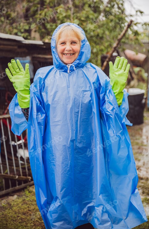 Preview: Vertical portrait of a beautiful happy elderly woman in a blue raincoat.