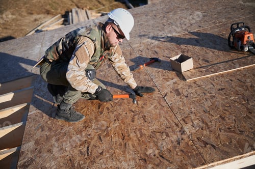 Preview: Carpenter hammering nail into OSB panel while building wooden frame house.