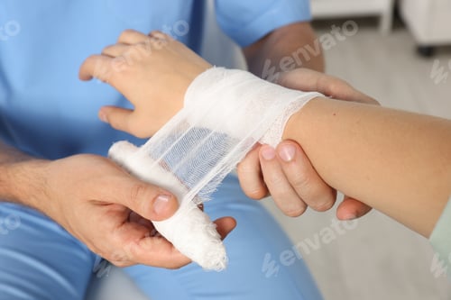 Preview: Doctor applying bandage onto patient's wrist in hospital, closeup