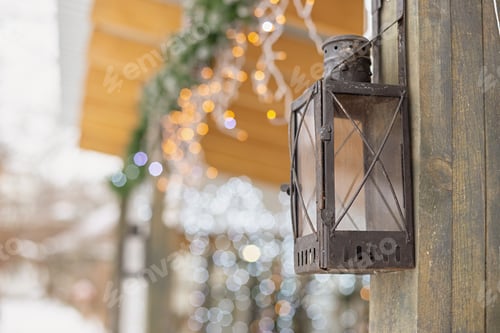 Preview: Antique street iron lantern hanging on the wooden post of a house