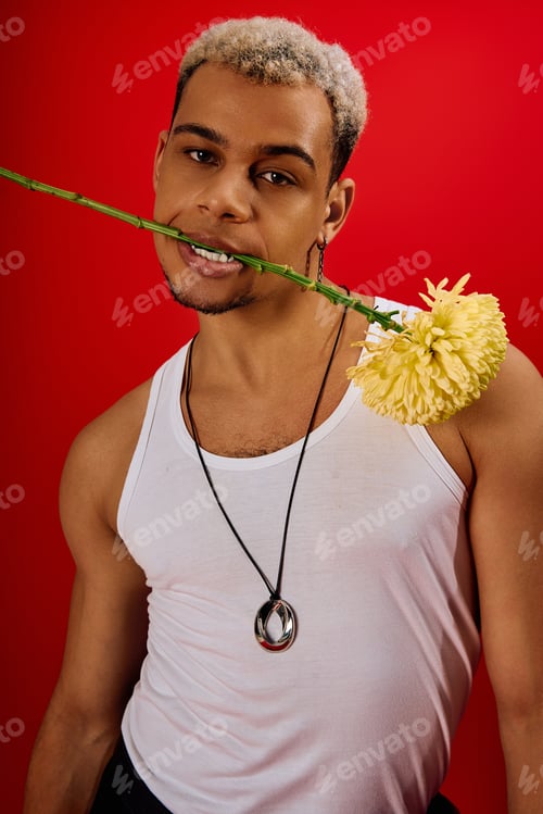 Preview: Young man exhibits trendy style with flower in vibrant red studio setting