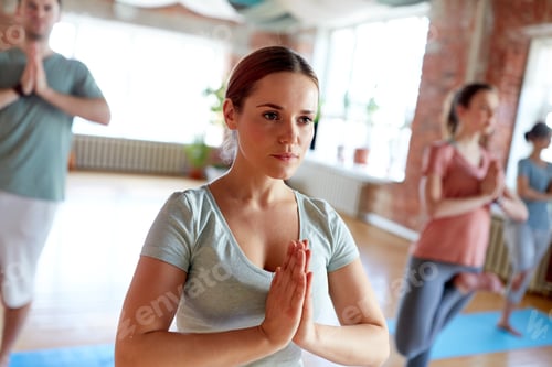 Preview: group of people doing yoga tree pose at studio