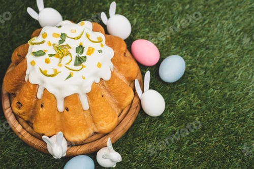Preview: High angle view of easter cake with colorful chicken eggs and decorative bunnies on green background