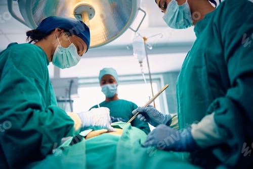 Preview: Female doctor performing surgery in operating room at medical clinic.