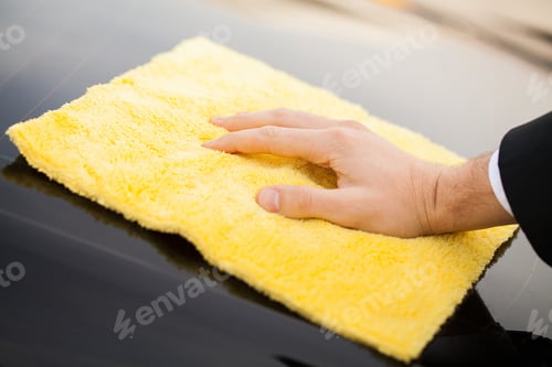 Preview: Cleaning car. Man holds the microfiber in hand and polishes the car