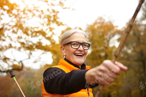 Preview: Senior woman enjoying Nordic walking in an autumn park