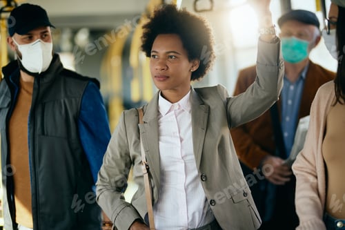 Preview: Black businesswoman without protective face mask among commuters in a bus.