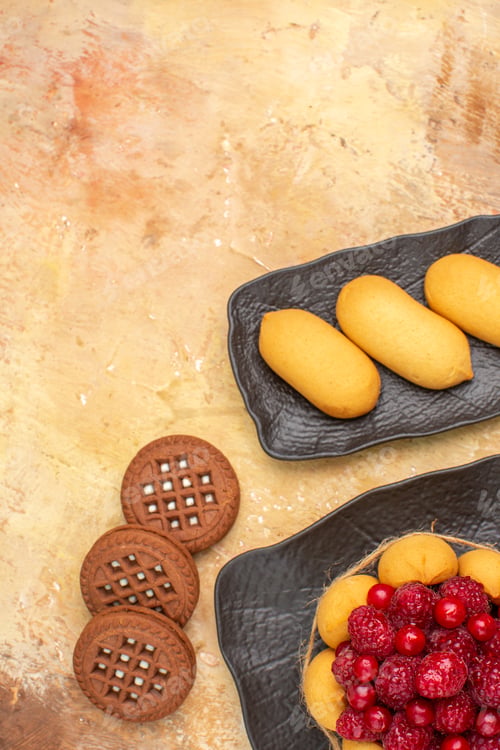Preview: Vertical view of a gift cake and biscuits on brown plates fruits on mixed color background