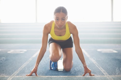 Preview: Young female athlete on starting blocks