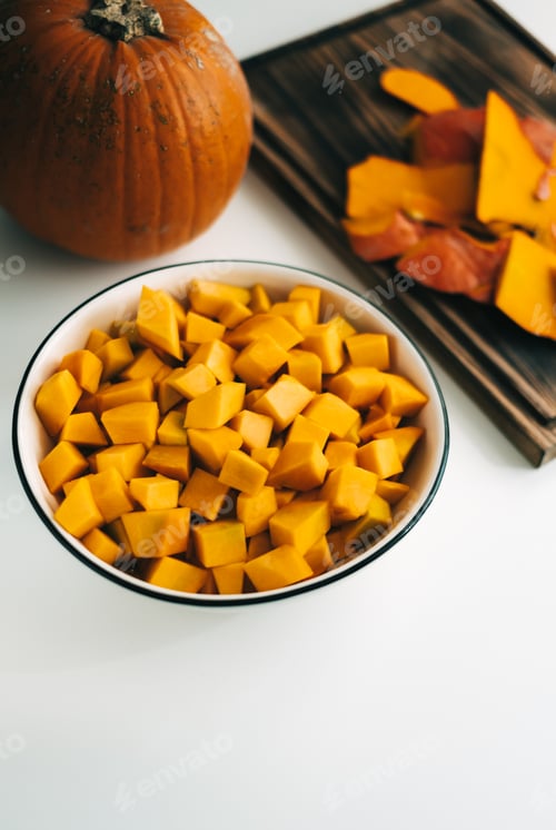 Preview: Close up view of fresh, vivid orange pumpkin pieces in a white plate. Healthy and nutritious food.