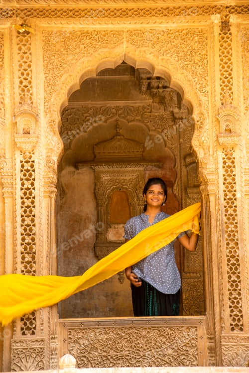 Preview: Young woman tourist in stone carved window, India.