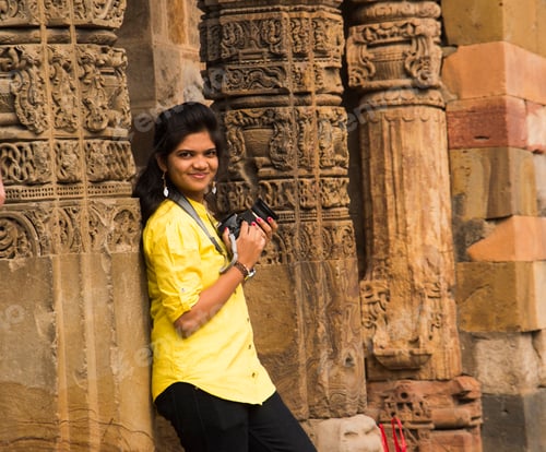 Preview: Young woman photographer with DSLR camera at Qutub Minar , Delhi, India.