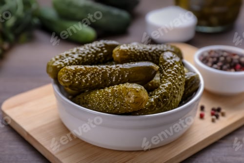 Preview: Bowl of pickled cucumbers and ingredients for food preservation on wooden table, closeup