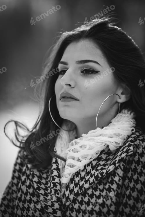 Preview: Black and white portrait of a beautiful woman in a fashionable winter outfit posing in a snowy park