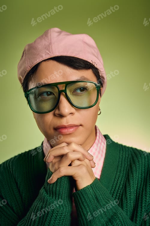 Preview: Stylish asian man with pink checkered shirt and cardigan in vibrant green setting