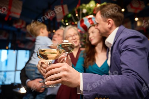 Preview: Family hold glasses of champagne congratulating each other with New Year while
