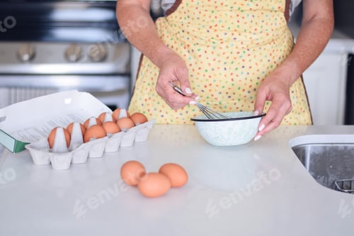 Preview: Woman is whisking eggs in a small mixing bowl