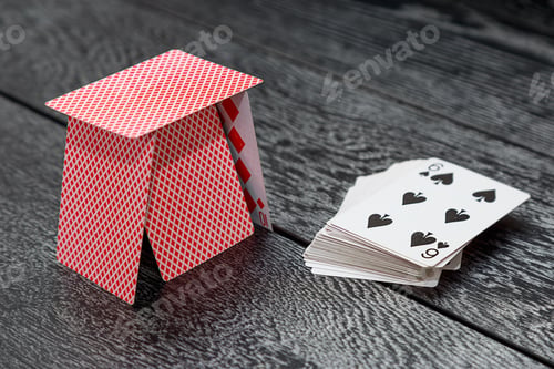 Preview: a house of playing cards and a deck of cards lies on a gray wooden table