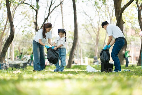 Preview: Happy Asian family collecting plastic bottles at the park.