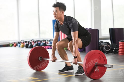 Preview: Young man lifting barbell at gym