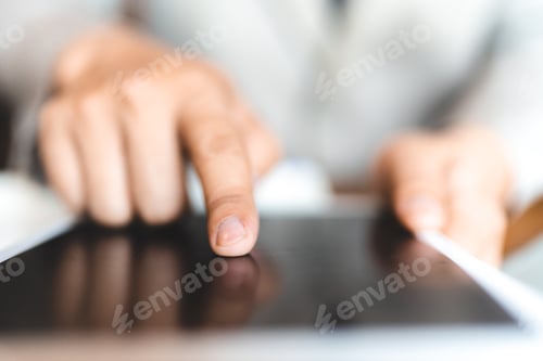 Preview: Hands of young man typing and working on digital tablet with financial and sales chart