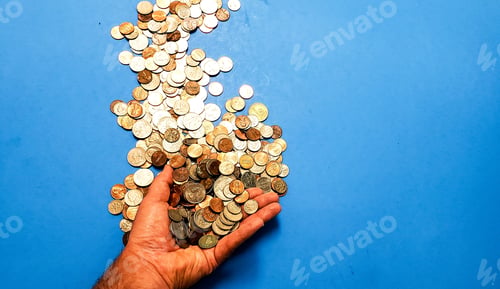 Preview: Overhead flat lay business and finance with hand holding coins on blue background with copy space.