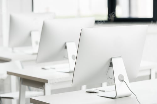 Preview: close up view of white computer monitors standing on tables in computer class