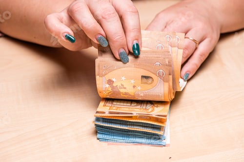 Preview: business, finance, saving, banking and people concept - close-up of woman hands counting euro money