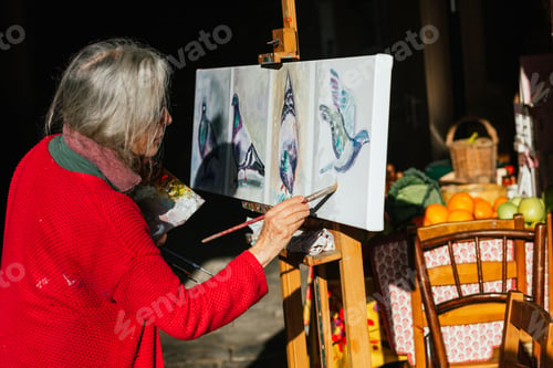 Preview: Senior woman painting on canvas in garden