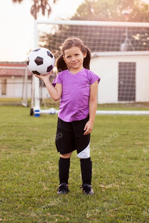 Preview: Portrait of girl football player holding up football on practice pitch