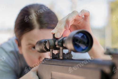 Preview: A female sniper adjusts an optical sight while looking into it