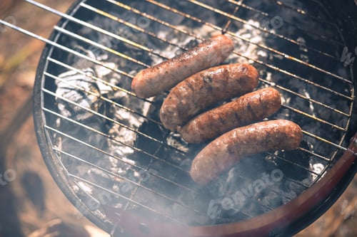 Preview: Close-up top view of grilling sausages on barbecue grill outdoors