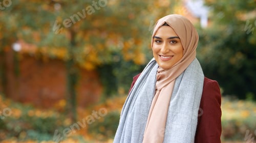 Preview: Head And Shoulders Portrait Of Smiling Young British Muslim Woman Wearing Hijab In Autumn Park