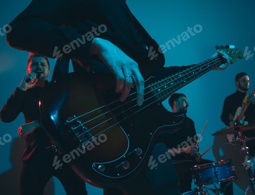 Preview: Young caucasian musicians, band performing in neon light on blue studio background, guitarist in