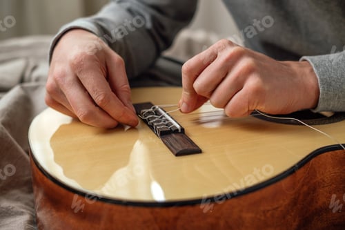 Preview: Man's hands tighten a new string on a guitar. Nominated