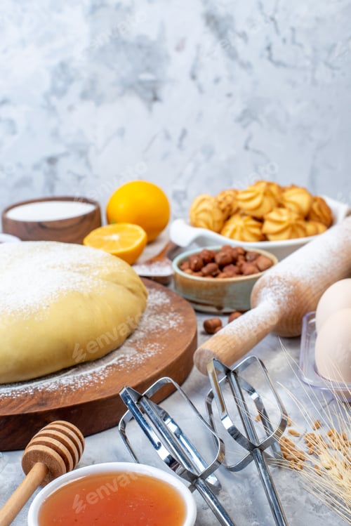 Preview: Front view of raw pastry on wooden round board and set of various foods grater on ice background