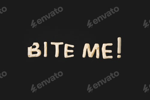 Preview: top view of lettering bite me made from cookie dough isolated on black