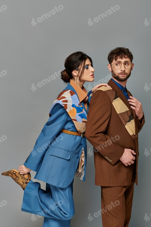 Preview: stylish man and woman in tailored suits, formal attire, grey backdrop, fashion shoot, couple, models