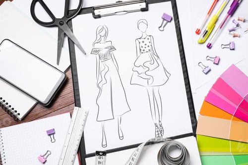 Preview: Sketch of stylish clothes and other fashion designer`s supplies on wooden table, flat lay
