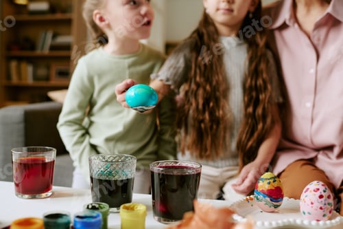 Preview: Two Girls Decorating Easter Eggs Together Indoors with Adult