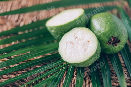 Preview: Tropical fruit feijoa over palm leaves on rattan background. Copy space. Acca sellowiana. Creative