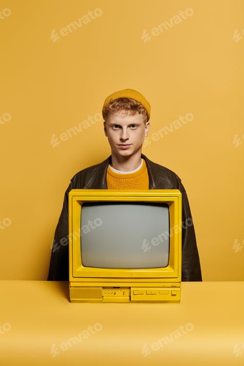 Preview: A fashionable young man with red hair showcases his winter attire leaning on a retro TV
