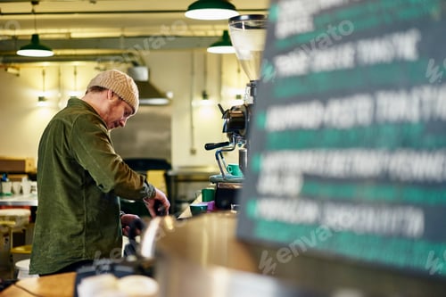 Vista previa: Dueño de cafetería masculino que trabaja en el mostrador de la cocina