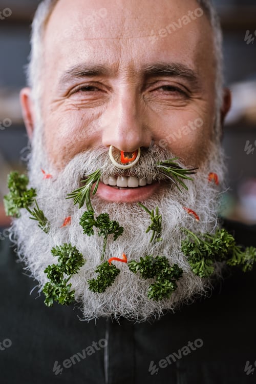 Preview: Close-up portrait of senior man with vegetables in beard smiling at camera