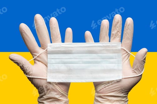 Preview: Doctor holding medical face mask in two hands on background National Ukrainian flag