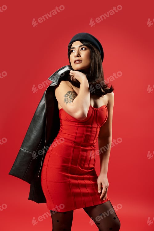 Preview: Stylish young woman showcases bold fashion against vibrant red backdrop in urban setting