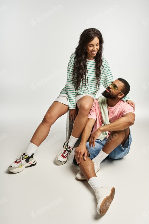 Preview: Stylish couple sharing a joyful moment while seated indoors in casual outfits and loving gazes